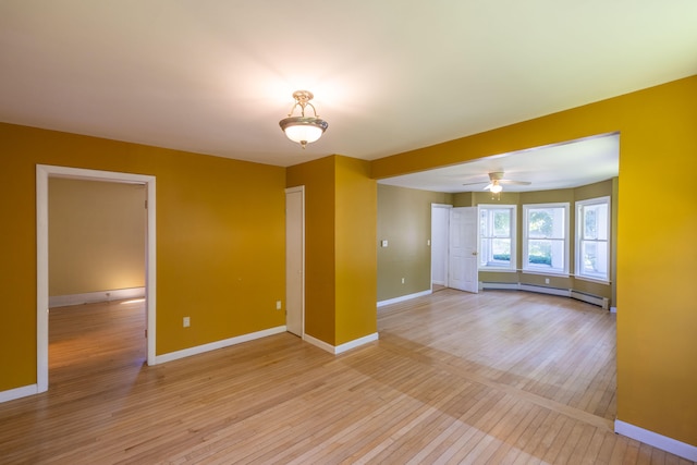 unfurnished room with a baseboard radiator, ceiling fan, and light hardwood / wood-style floors