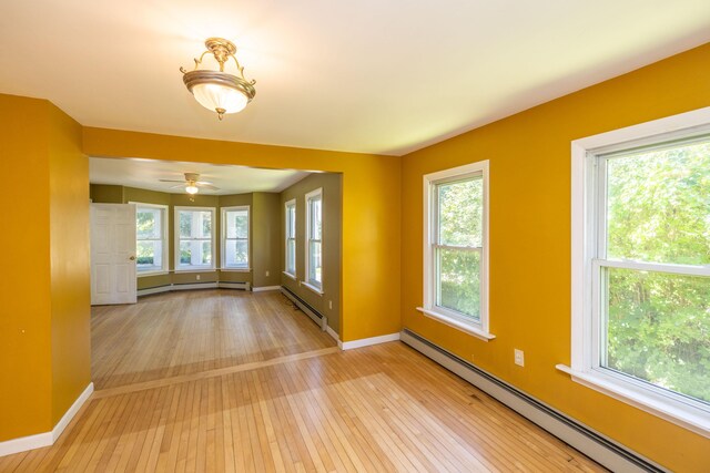 spare room with a baseboard heating unit, a wealth of natural light, and light hardwood / wood-style flooring