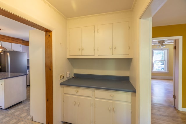 kitchen featuring light wood-type flooring, crown molding, stainless steel fridge, ceiling fan, and white cabinets