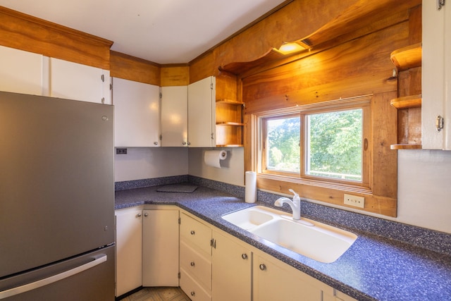 kitchen with stainless steel fridge, white cabinetry, and sink