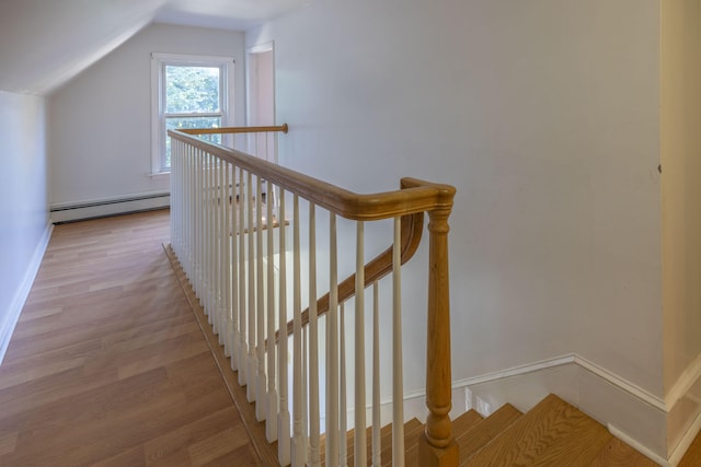 stairs featuring a baseboard radiator, wood-type flooring, and vaulted ceiling