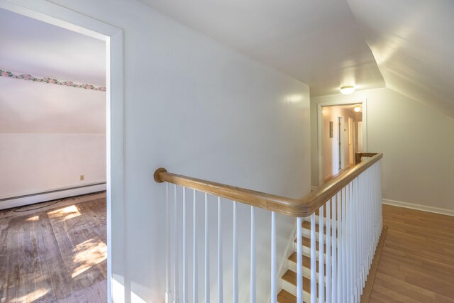 corridor featuring vaulted ceiling, a baseboard radiator, and light hardwood / wood-style flooring