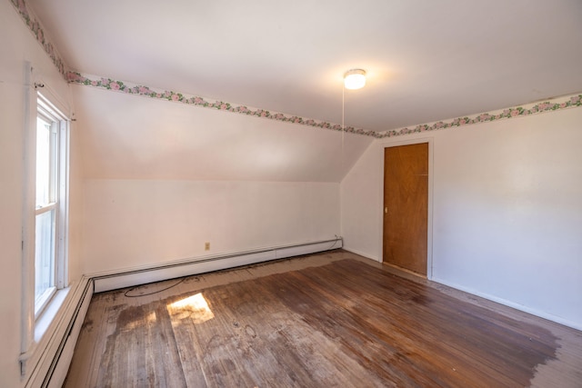 spare room featuring lofted ceiling, a wealth of natural light, baseboard heating, and dark hardwood / wood-style flooring