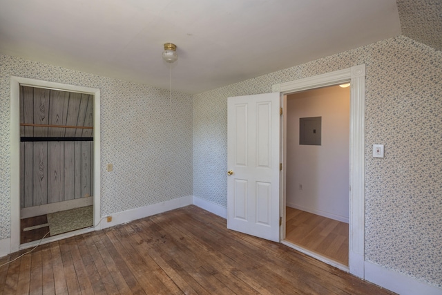 unfurnished bedroom with electric panel and hardwood / wood-style flooring