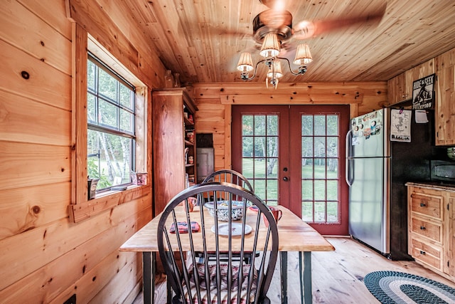 dining area featuring french doors, wooden ceiling, light hardwood / wood-style floors, and wood walls