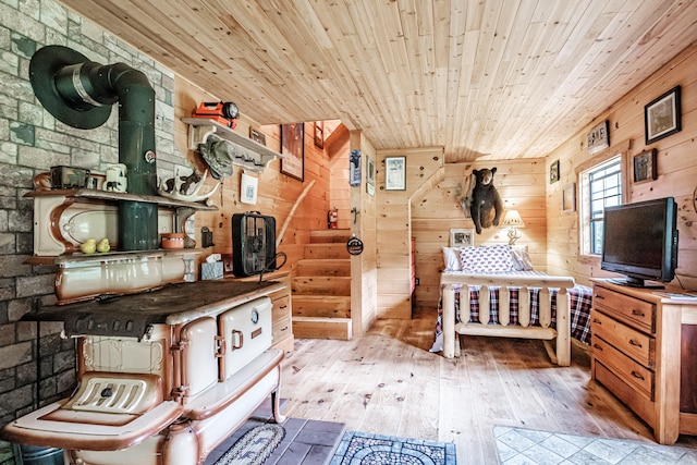 bedroom featuring a wood stove, light hardwood / wood-style floors, wooden walls, and wooden ceiling