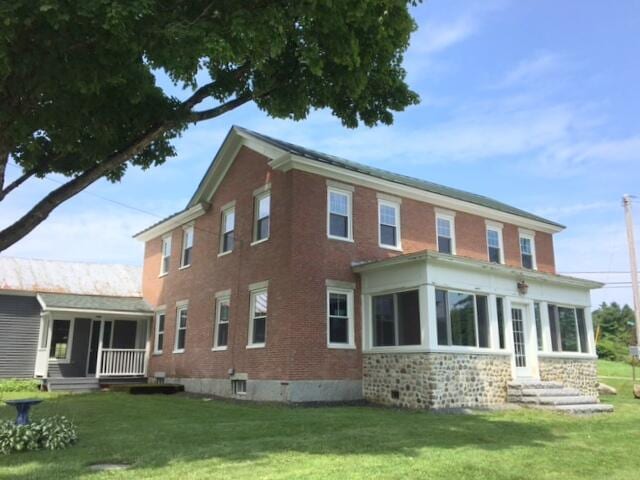 rear view of property featuring a sunroom and a yard