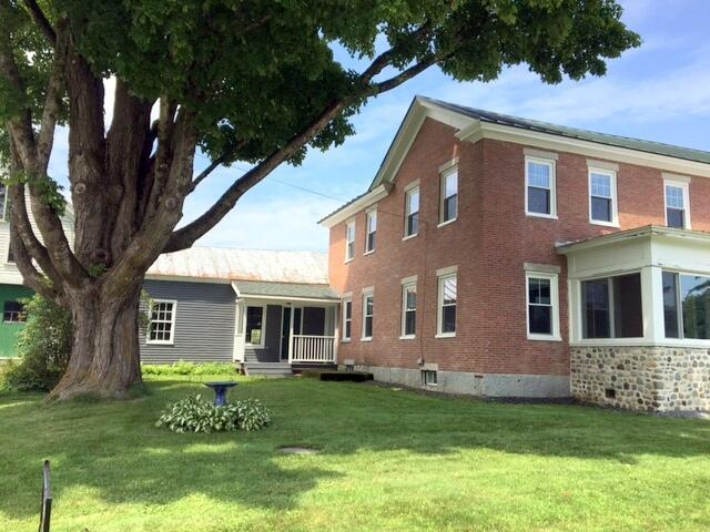 rear view of house with a lawn and brick siding