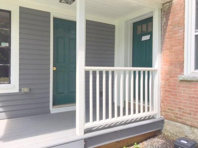 doorway to property with brick siding and covered porch