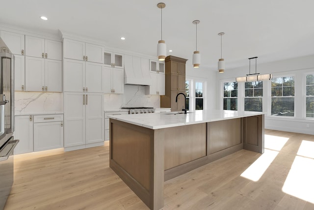 kitchen featuring white cabinetry, a center island with sink, and sink