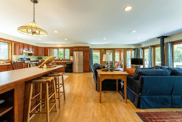 interior space featuring open floor plan, decorative light fixtures, freestanding refrigerator, light countertops, and gas range gas stove