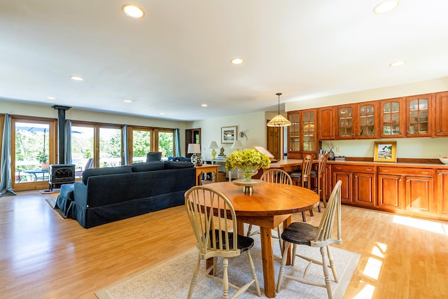 dining space with light hardwood / wood-style flooring and a wood stove