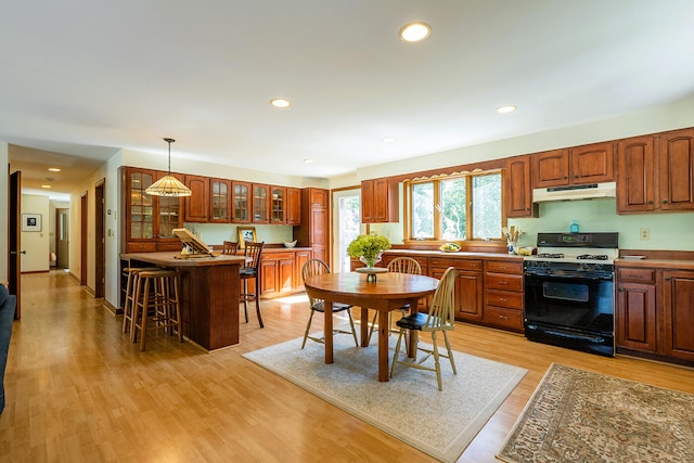 kitchen featuring light hardwood / wood-style flooring, a breakfast bar area, hanging light fixtures, and range with gas stovetop