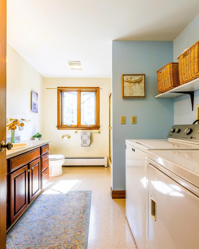 clothes washing area with washing machine and clothes dryer and a baseboard heating unit