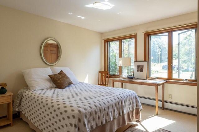 bedroom featuring a baseboard heating unit and light colored carpet