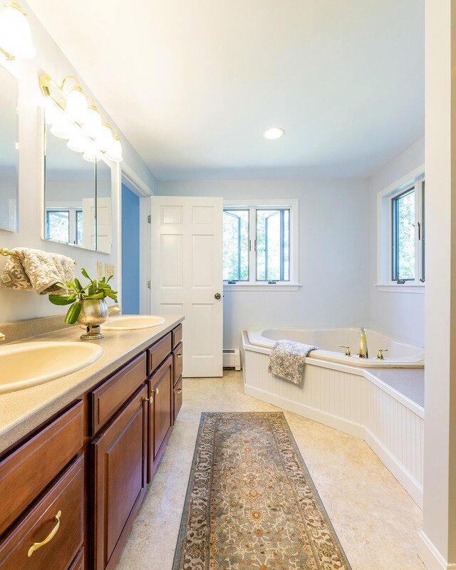 bathroom featuring plenty of natural light, baseboard heating, and a sink