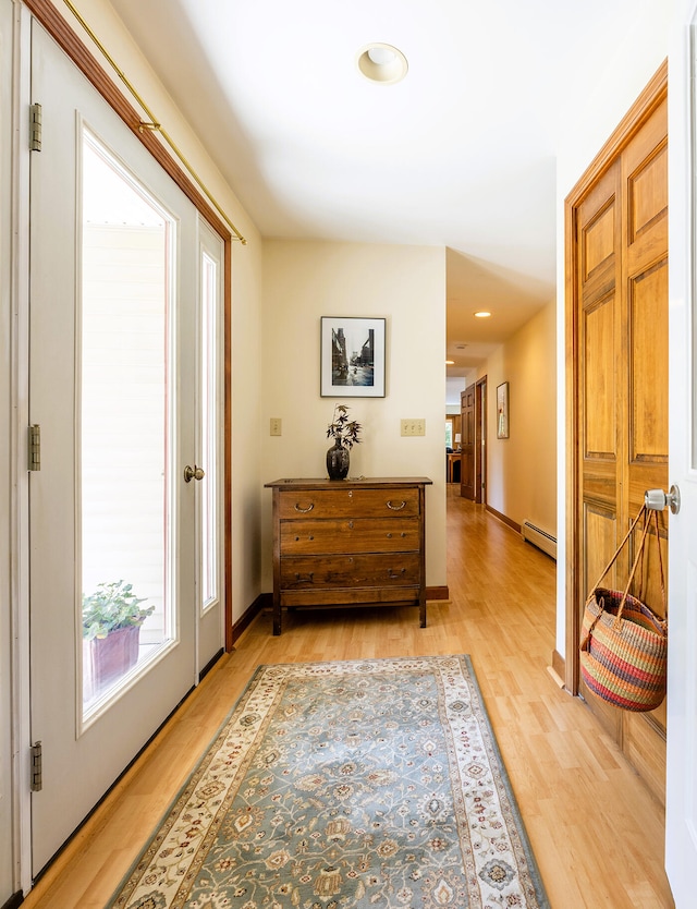 hallway with light hardwood / wood-style floors and a baseboard radiator