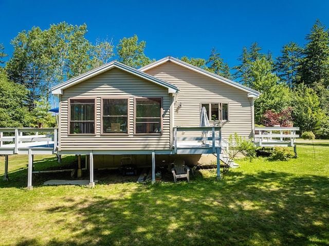 rear view of house featuring a wooden deck and a yard