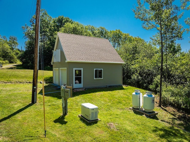 exterior space with a garage, a shingled roof, and a yard