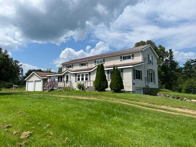 front facade with a garage, an outbuilding, and a front yard