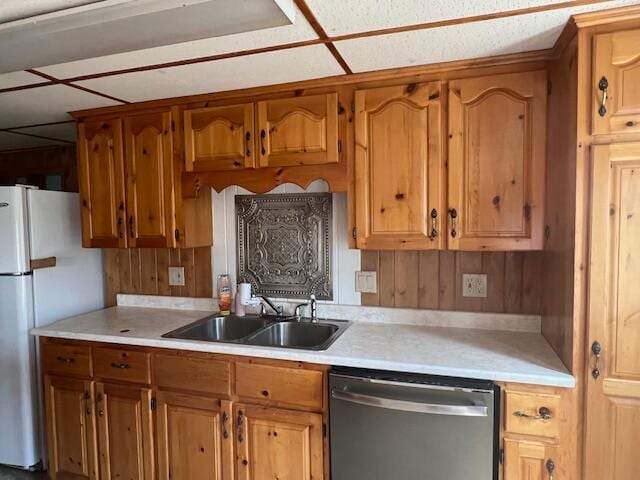 kitchen featuring sink, dishwasher, white fridge, and a drop ceiling