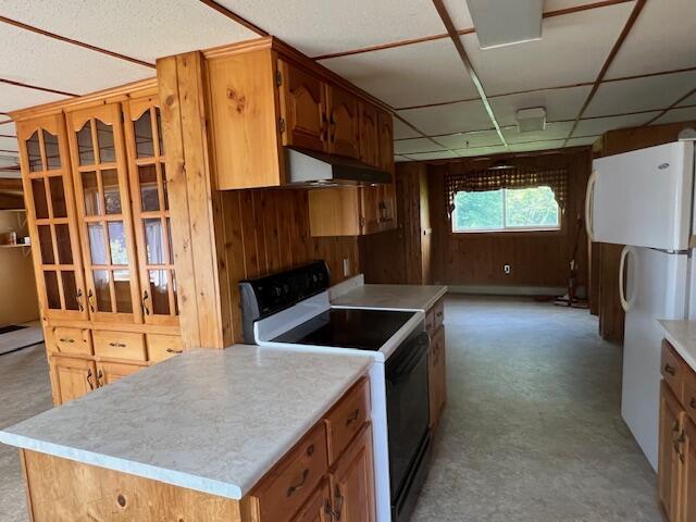 kitchen featuring concrete flooring, wall chimney exhaust hood, a drop ceiling, and white appliances