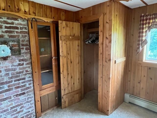 unfurnished bedroom with wood walls, a closet, and baseboard heating