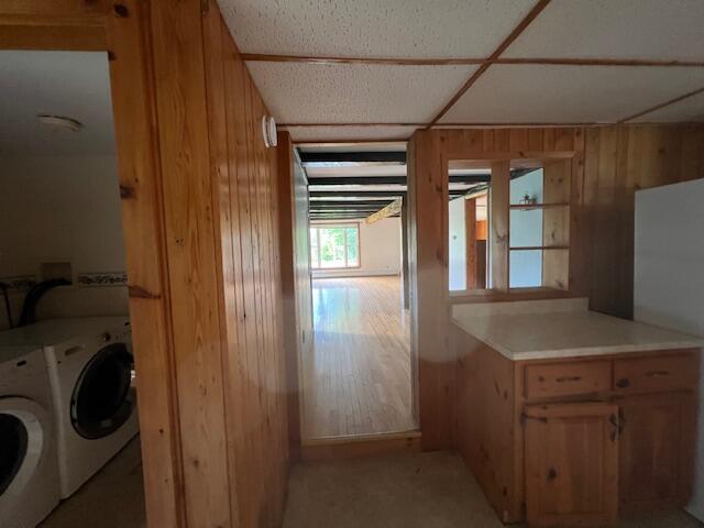 laundry area with washing machine and clothes dryer and wooden walls