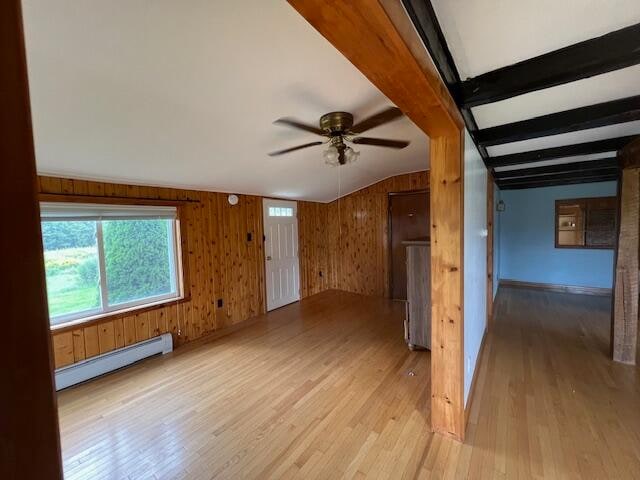 additional living space with lofted ceiling with beams, wooden walls, a baseboard heating unit, light hardwood / wood-style floors, and ceiling fan