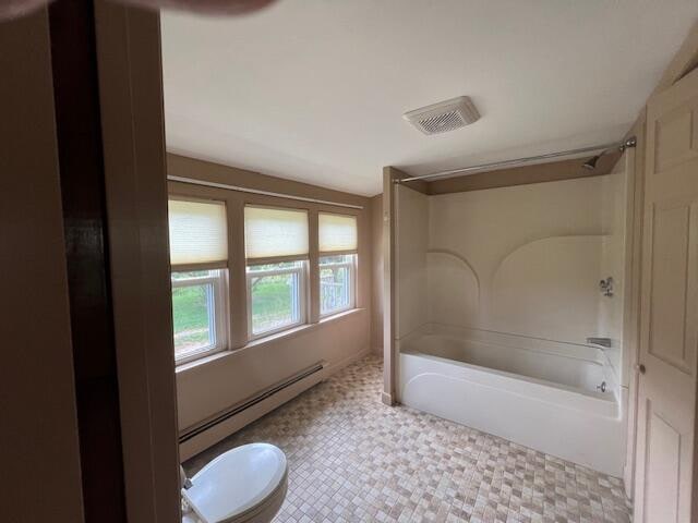 bathroom with tile patterned flooring, lofted ceiling, bathtub / shower combination, toilet, and baseboard heating