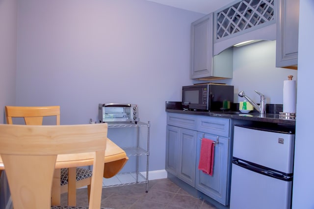 kitchen featuring refrigerator, sink, and light tile patterned floors