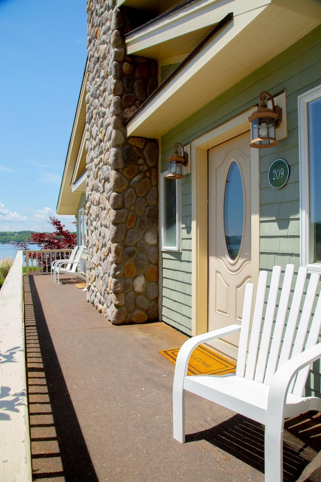 view of exterior entry with a balcony and a water view