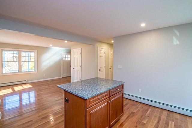 kitchen featuring stone counters, a baseboard radiator, hardwood / wood-style floors, and a center island