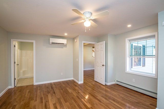 spare room with a wall mounted AC, a baseboard heating unit, hardwood / wood-style flooring, and ceiling fan