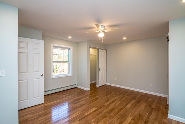 spare room with dark wood-type flooring, a baseboard radiator, and ceiling fan