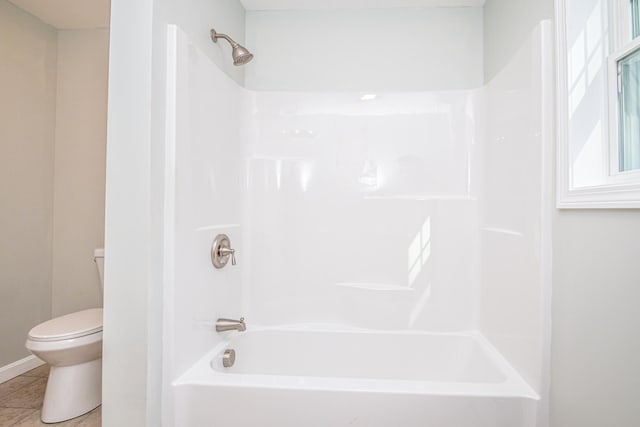 bathroom with toilet, washtub / shower combination, and tile patterned flooring