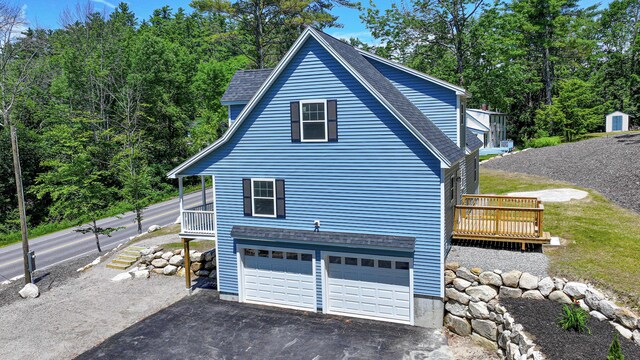 363 Main St, Fryeburg, ME 04037 - view of home's exterior featuring driveway, a garage, a wooden deck, and roof with shingles