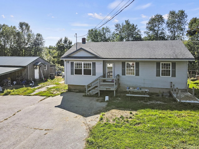 single story home with a chimney, roof with shingles, and driveway