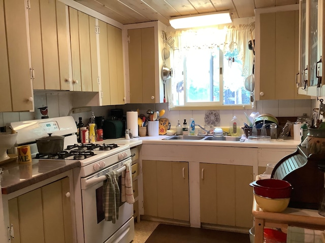 kitchen with white range with gas stovetop, sink, and cream cabinets