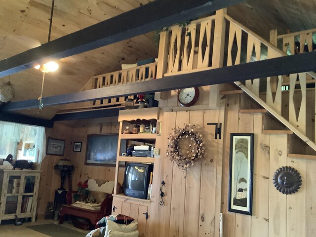 living room with wooden walls, vaulted ceiling with beams, and wooden ceiling