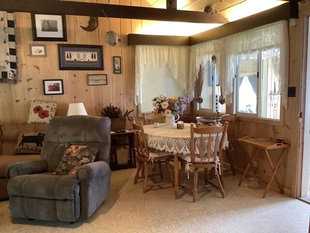 carpeted dining space featuring wood walls