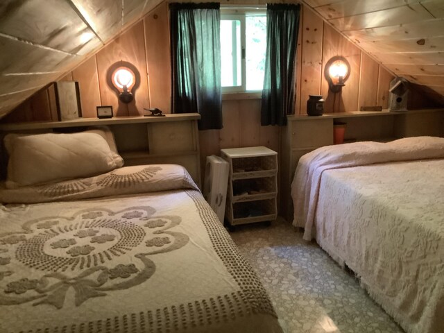 bedroom featuring lofted ceiling and wood walls