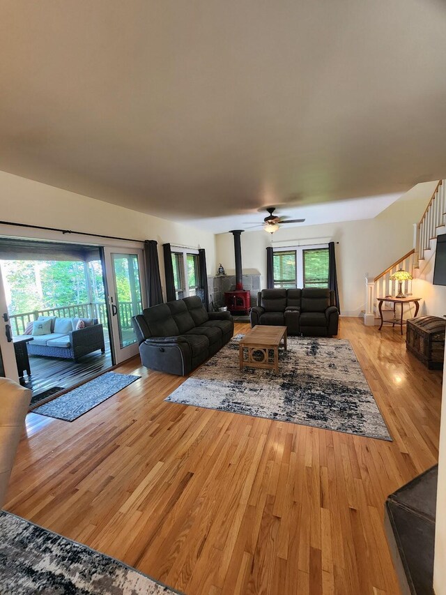 living room featuring a wood stove, ceiling fan, and light wood-type flooring