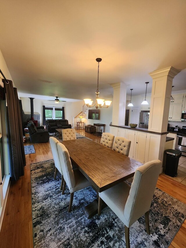 dining area with hardwood / wood-style flooring, ceiling fan with notable chandelier, and ornate columns