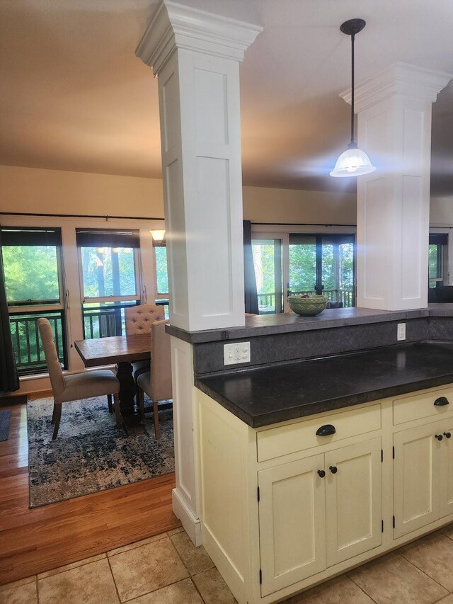 kitchen featuring a wealth of natural light, hanging light fixtures, white cabinets, and light hardwood / wood-style floors