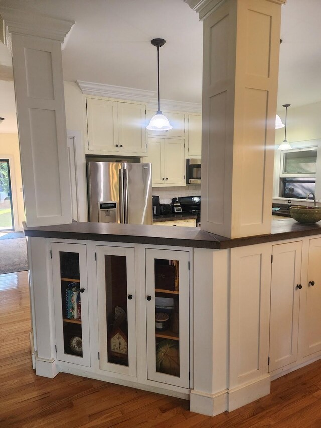 kitchen featuring hanging light fixtures, white cabinets, backsplash, and stainless steel appliances