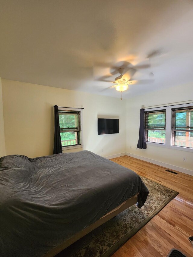 bedroom featuring multiple windows, light wood-type flooring, and ceiling fan