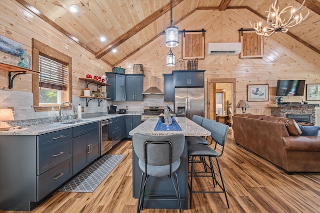 kitchen featuring light hardwood / wood-style floors, light stone countertops, hanging light fixtures, and appliances with stainless steel finishes