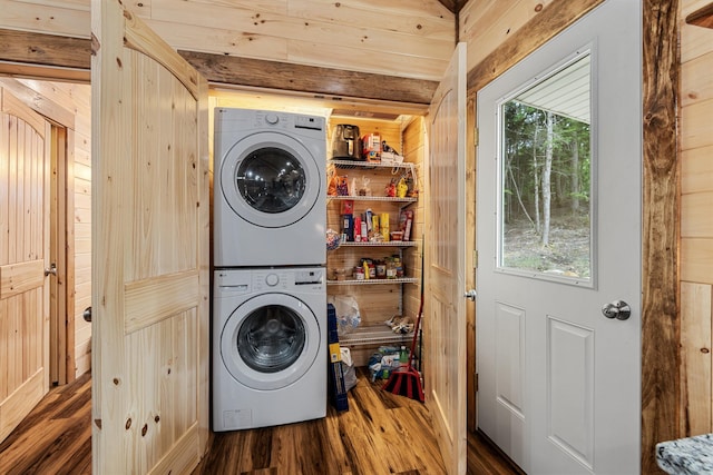 clothes washing area with wood walls, stacked washer / drying machine, and dark wood-type flooring