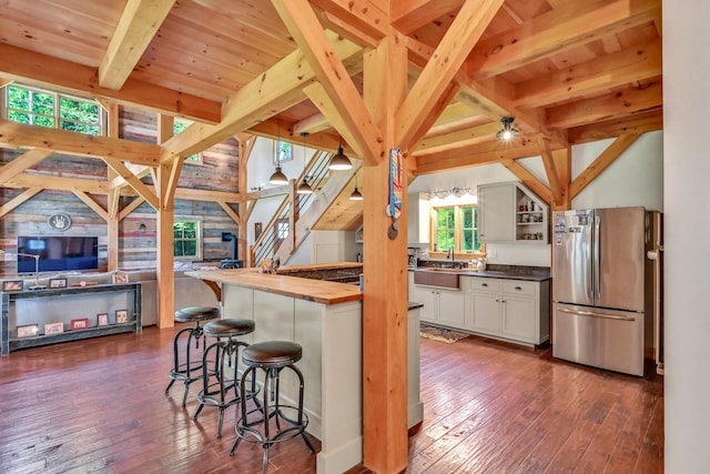 kitchen with sink, butcher block countertops, stainless steel refrigerator, dark hardwood / wood-style floors, and a kitchen bar